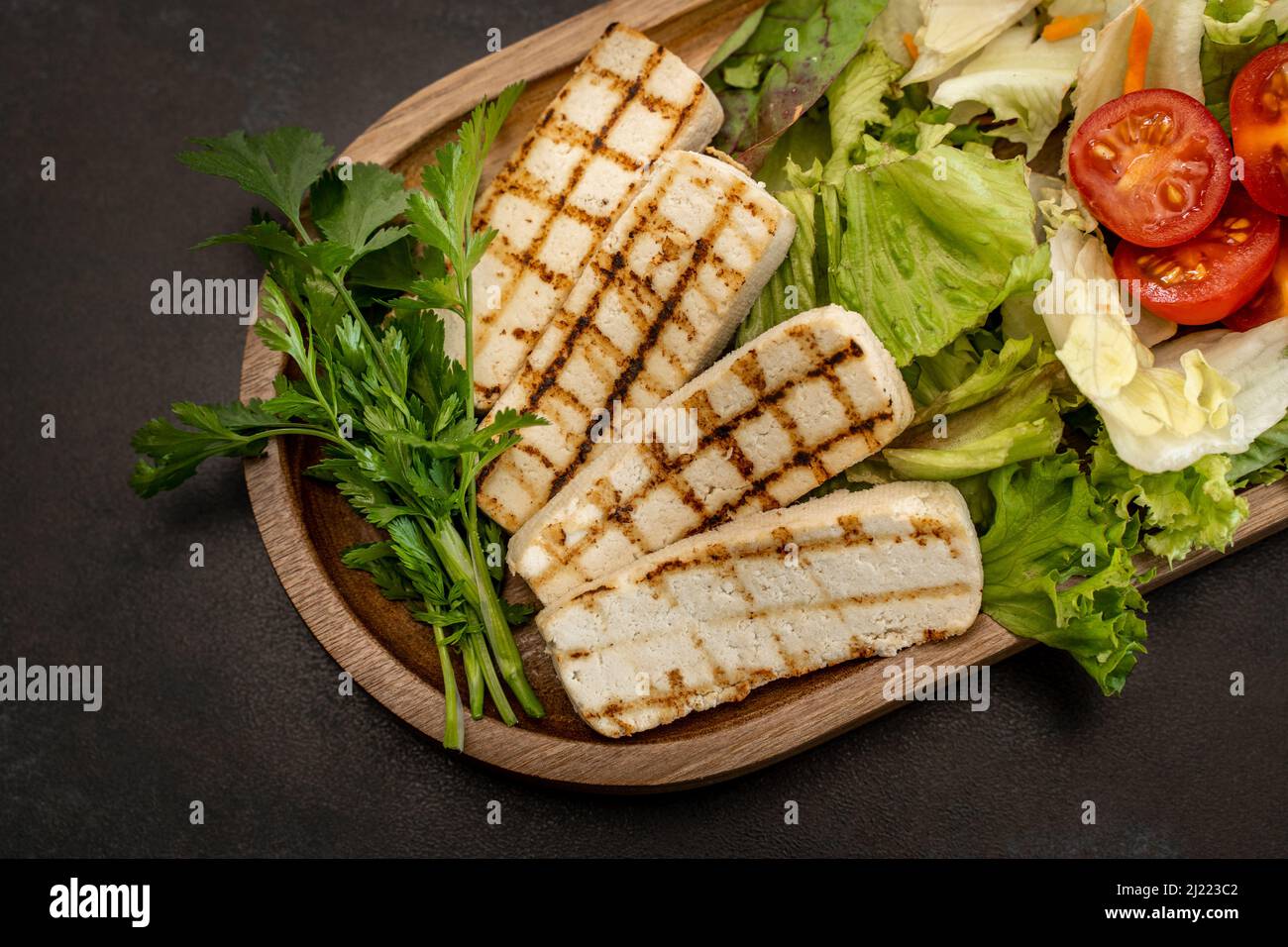 A top view of a vegetarian dish with grilled hellim cheese in a wooden tray Stock Photo