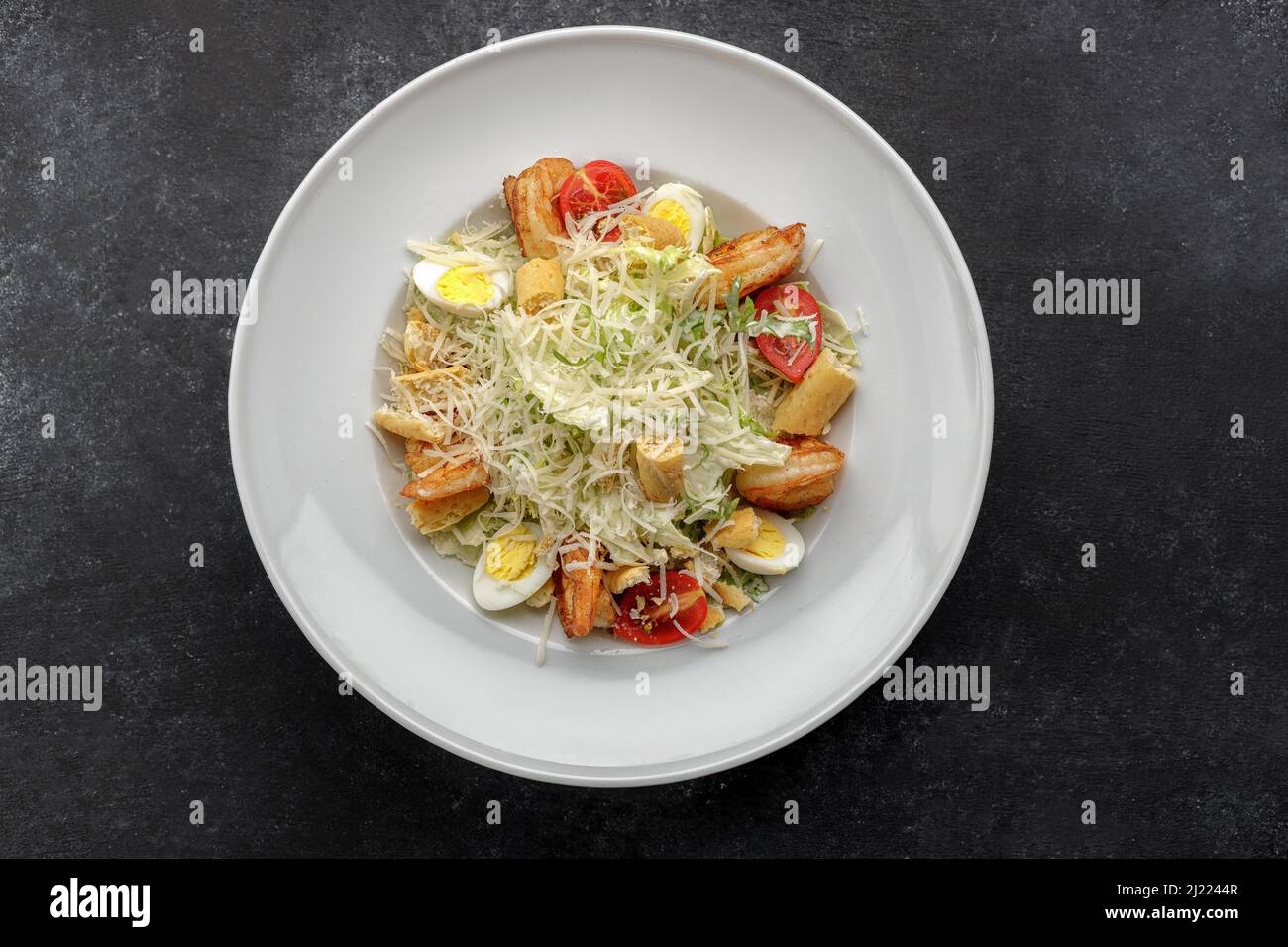 Caesar salad with shrimps, on a dark background. Stock Photo