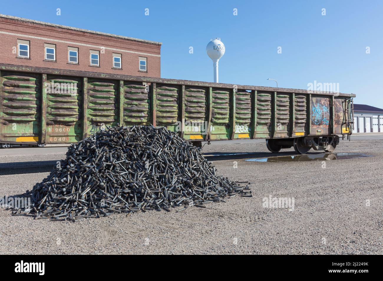 Railroad depot, a boxcar train wagon and a heap of discarded metal pins, track spikes. Stock Photo