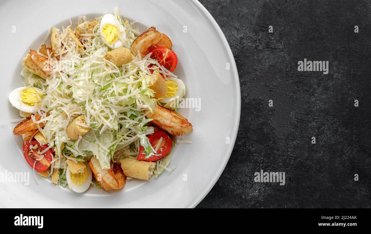 Caesar salad with shrimps, on a dark background. Stock Photo