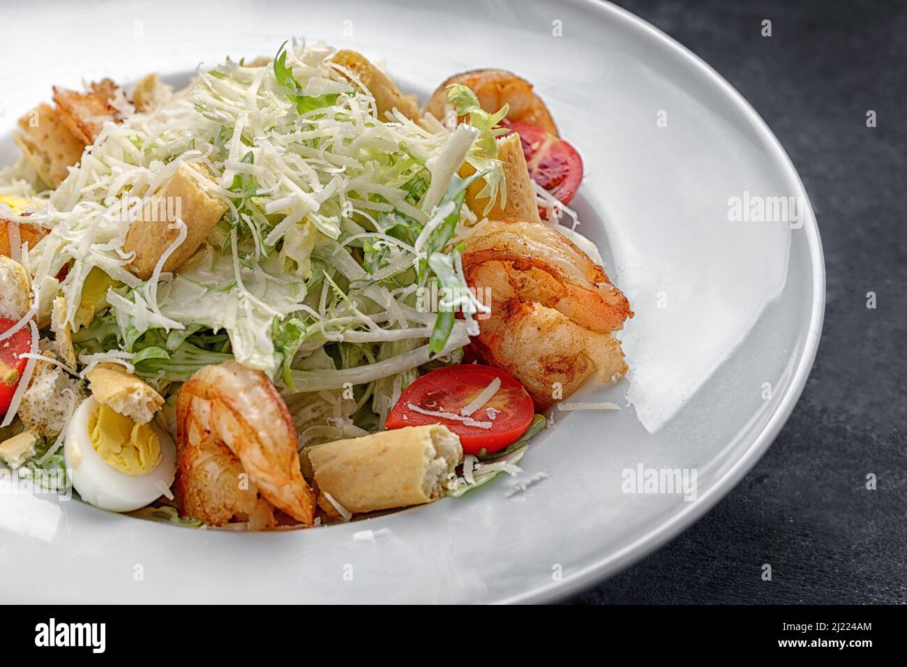 Caesar salad with shrimps, on a dark background. Stock Photo