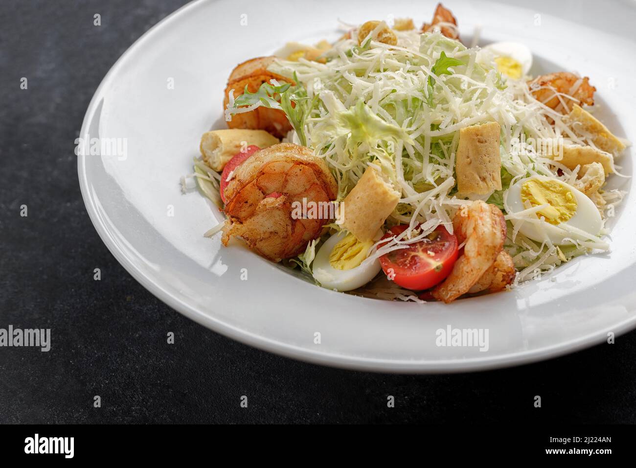 Caesar salad with shrimps, on a dark background. Stock Photo