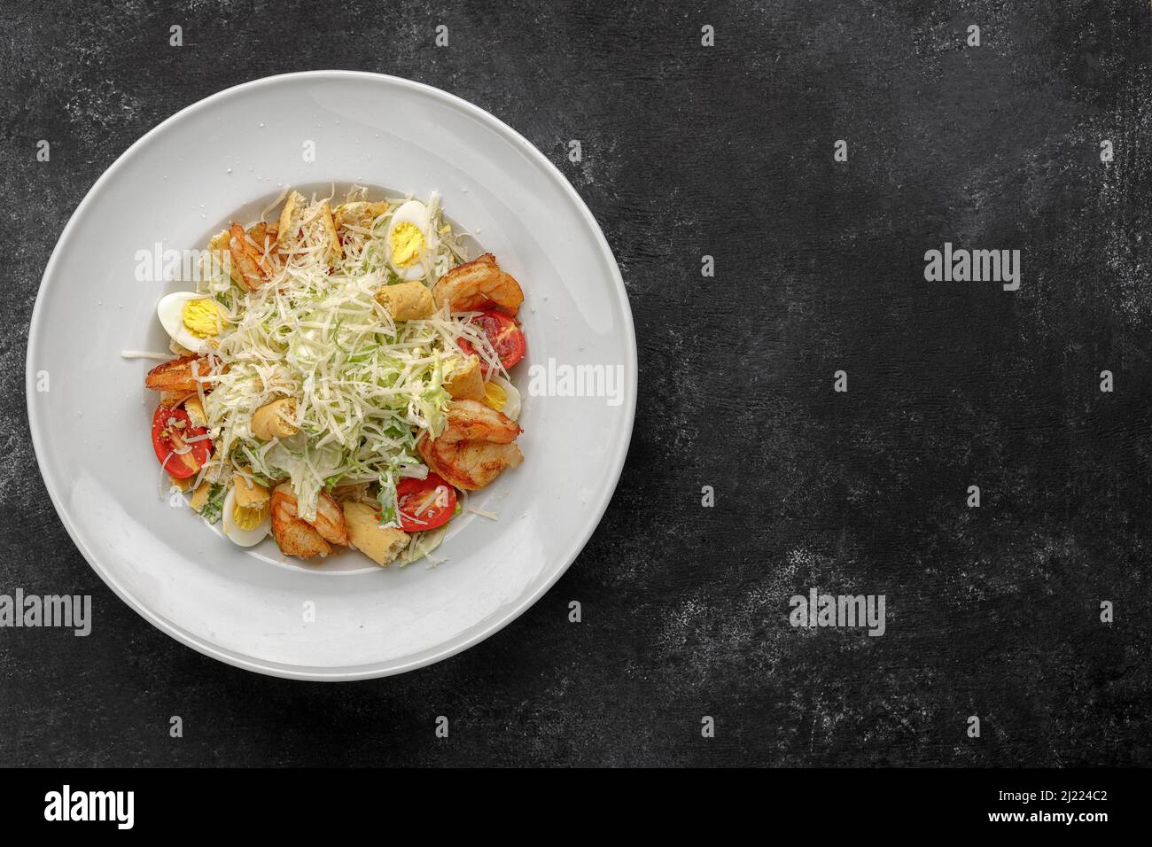 Caesar salad with shrimps, on a dark background. Stock Photo