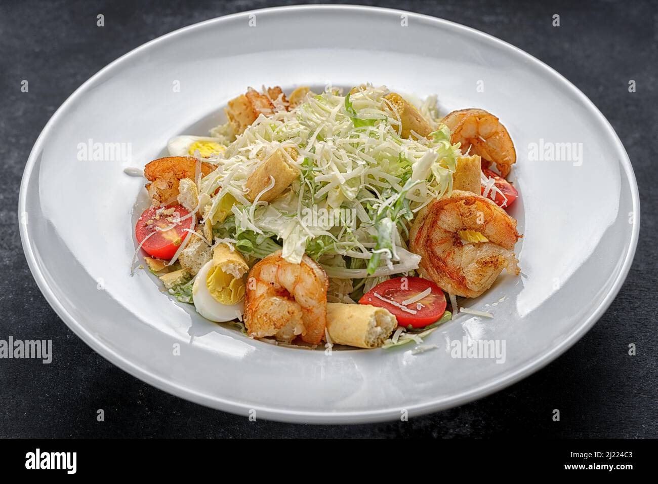 Caesar salad with shrimps, on a dark background. Stock Photo