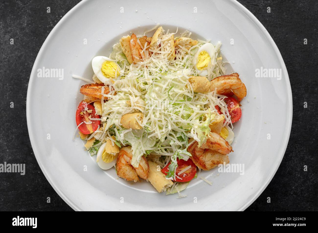 Caesar salad with shrimps, on a dark background. Stock Photo