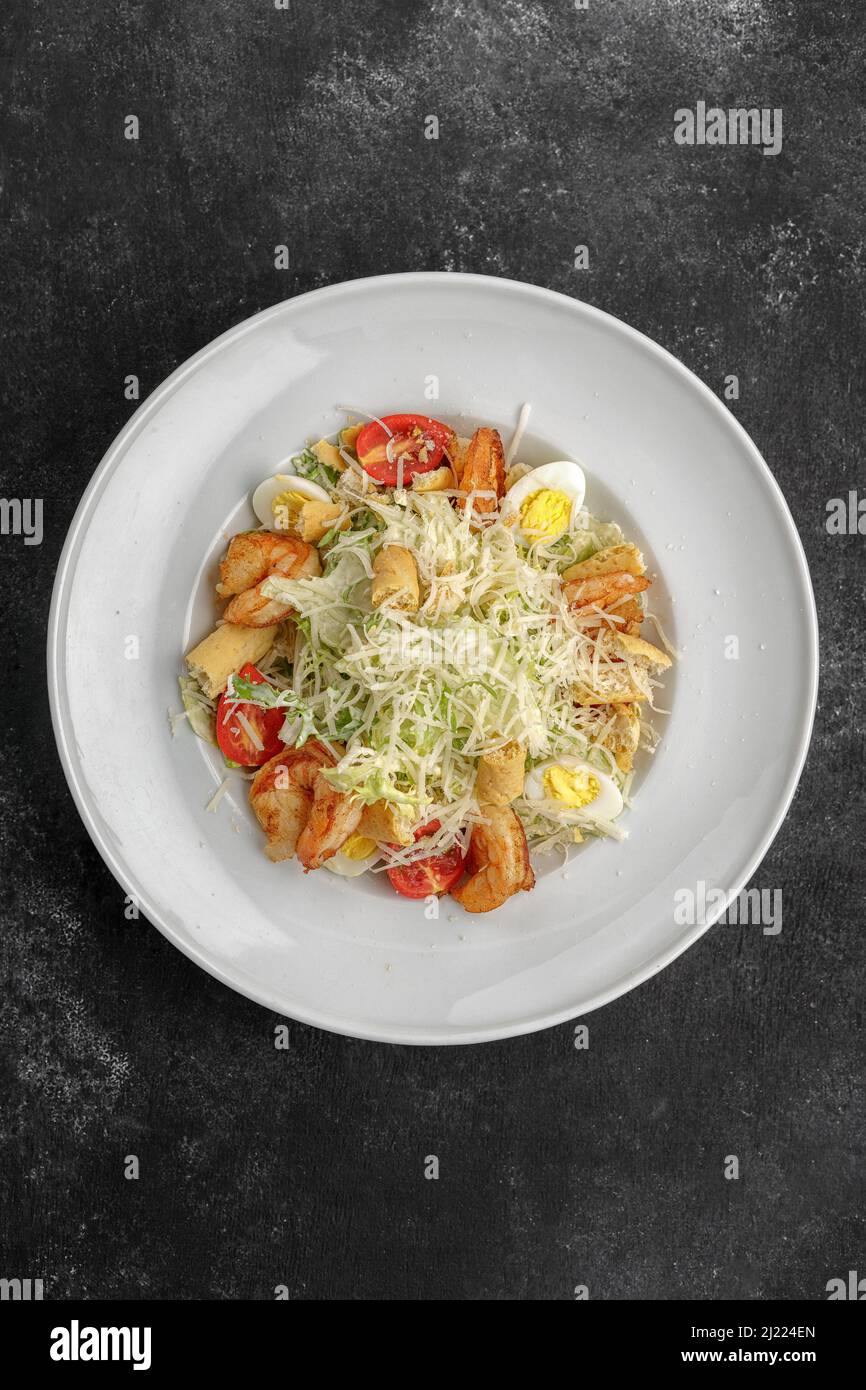 Caesar salad with shrimps, on a dark background. Stock Photo