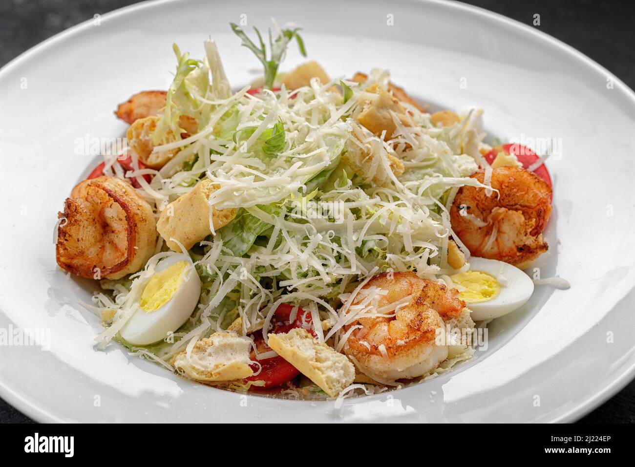 Caesar salad with shrimps, on a dark background. Stock Photo