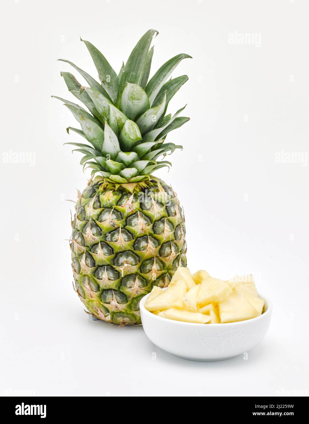 Pineapple and bowl of chunks on a white background Stock Photo Alamy