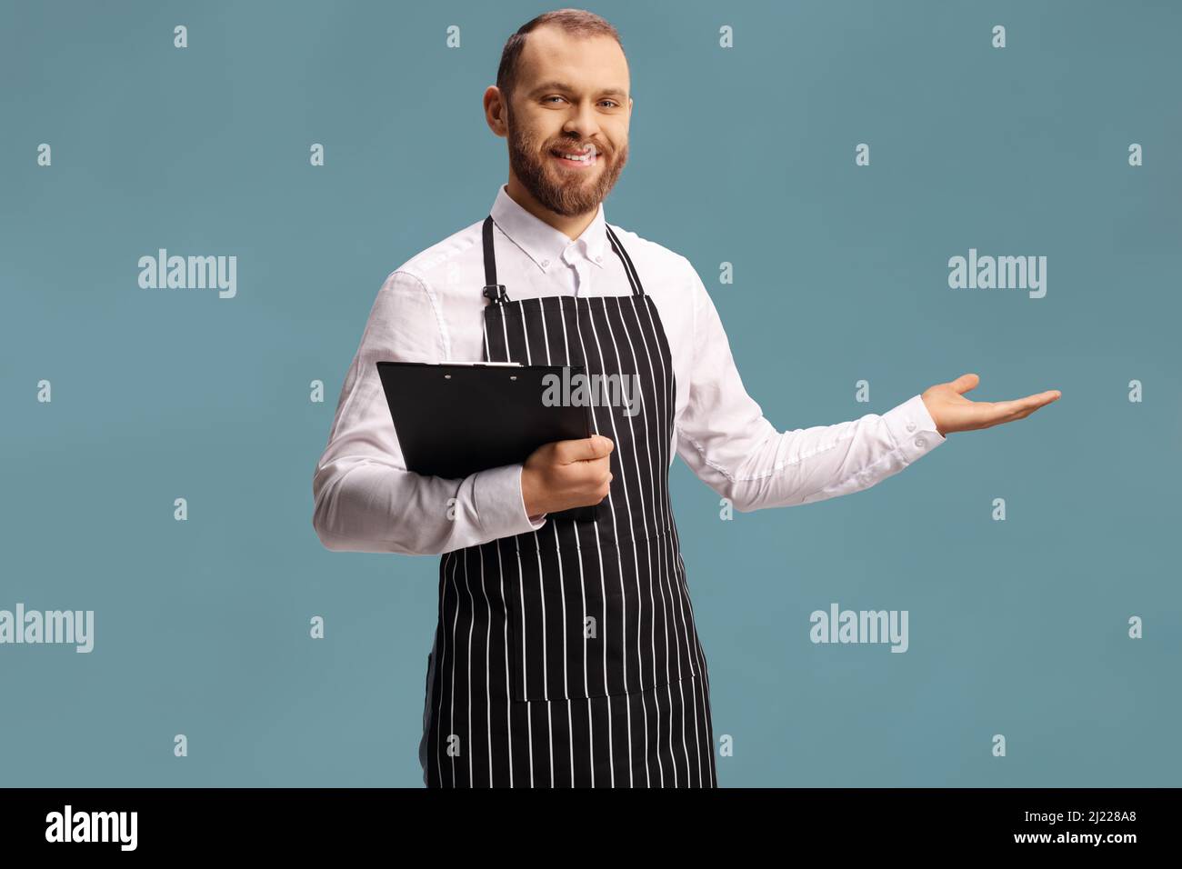 Waiter holding a menu and showing with hand isolated on blue background