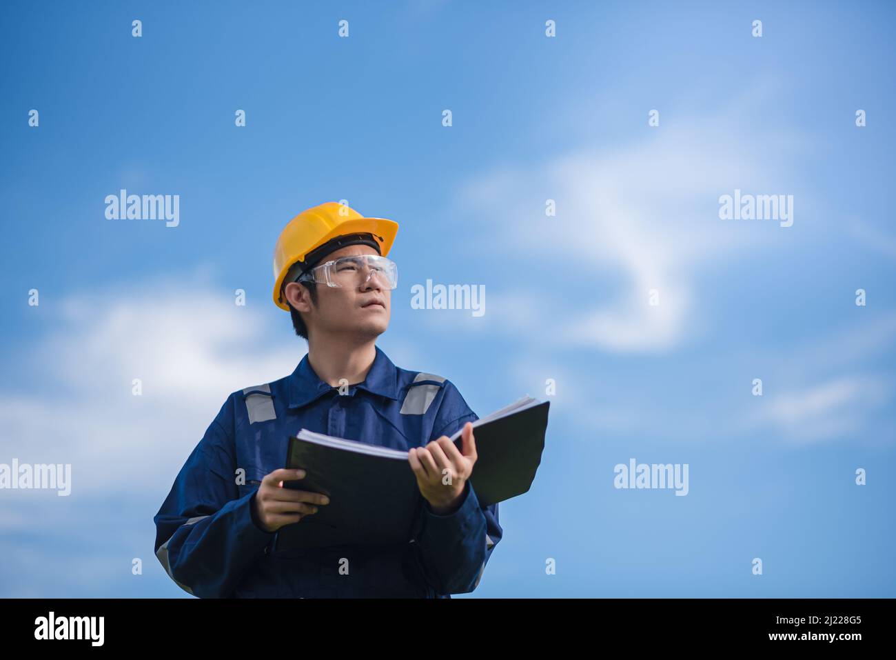 An Engineer is holding a document and looking away. Stock Photo