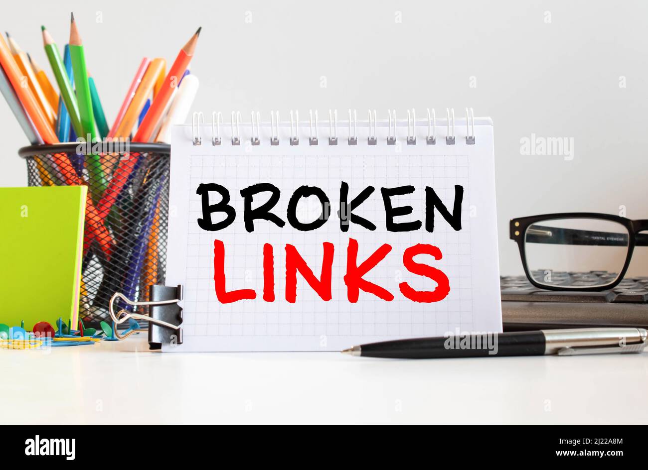 Broken links seo business concept text on a white background with a hourglass and an open book