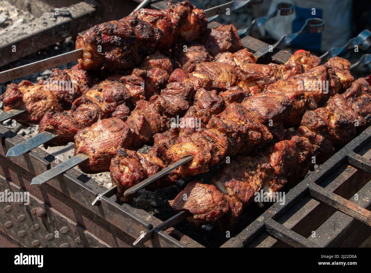 Grilling marinated shashlik preparing on a barbecue grill over charcoal.  Shashlik is a form of Shish kebab popular in Eastern Europe. Shashlyk (meaning  skewered meat) was originally made of lamb. Stock Photo