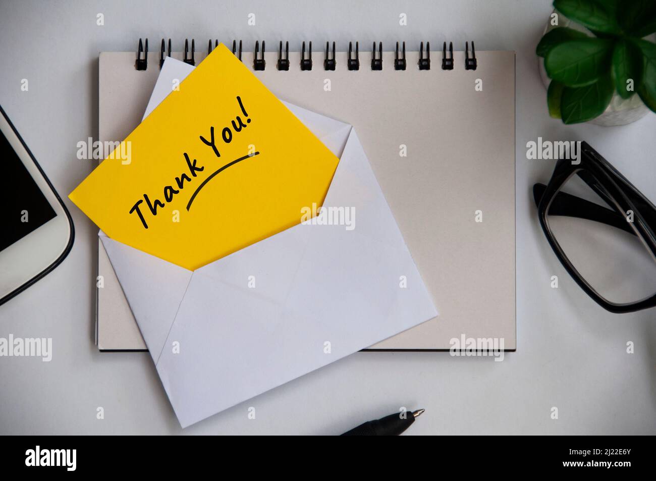 Thank you note on yellow paper in an envelope with office background