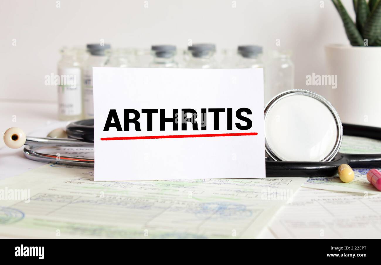 Arthritis text on card and hand holding it. Medicine concept Stock