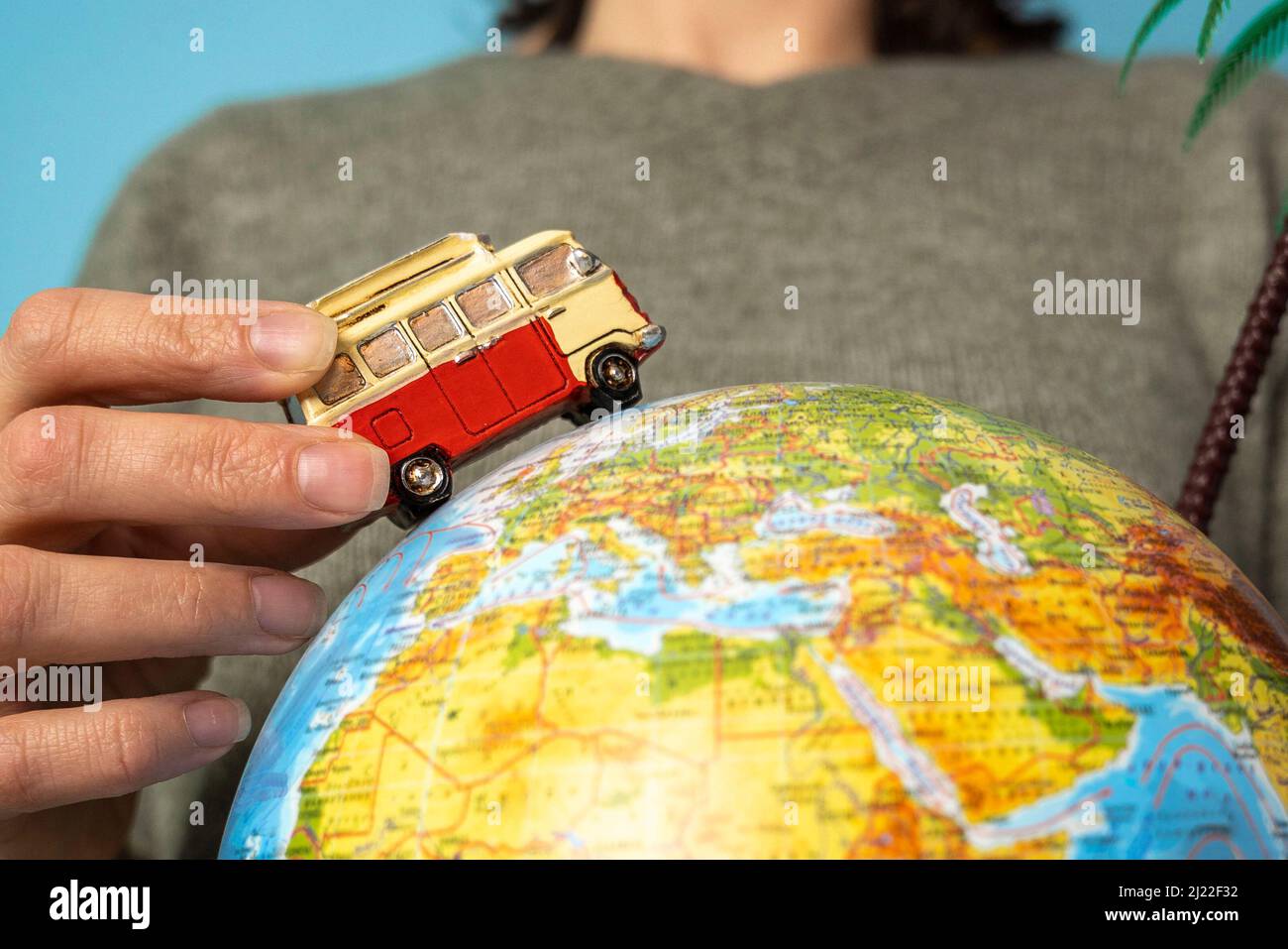 The concept of road trips - a toy car rides on a globe in the hands of a girl Stock Photo