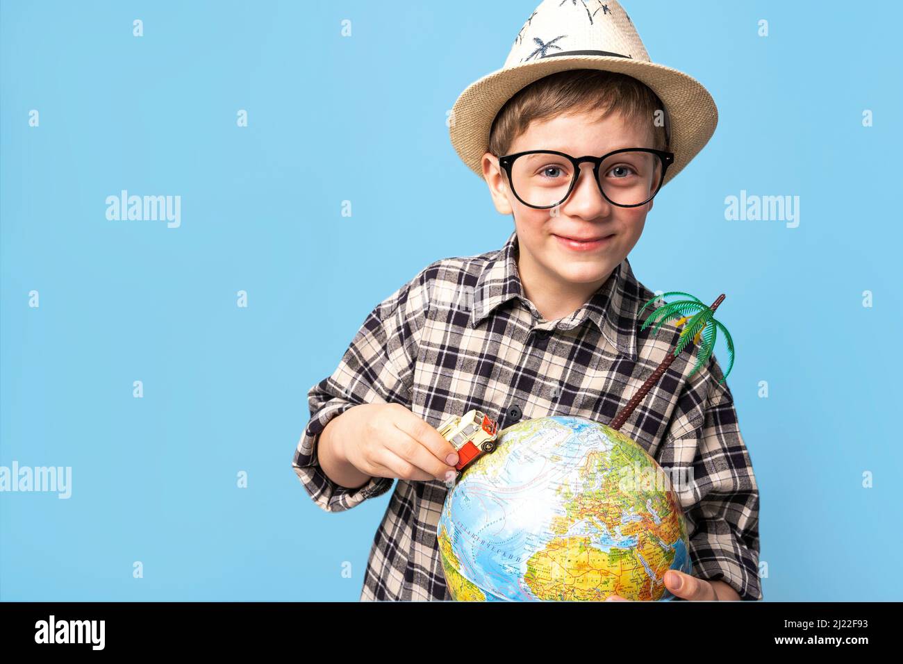 happy boy in a hat from the sun rides around the globe in a toy car Stock Photo