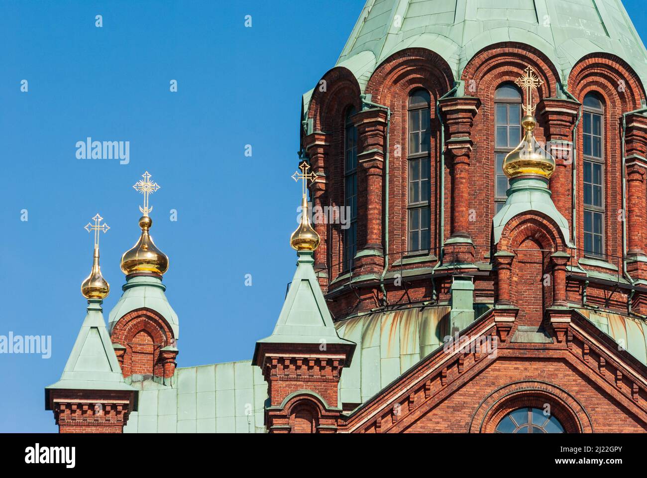 Red brick Uspenski Cathedral with green roof and gided crosses in