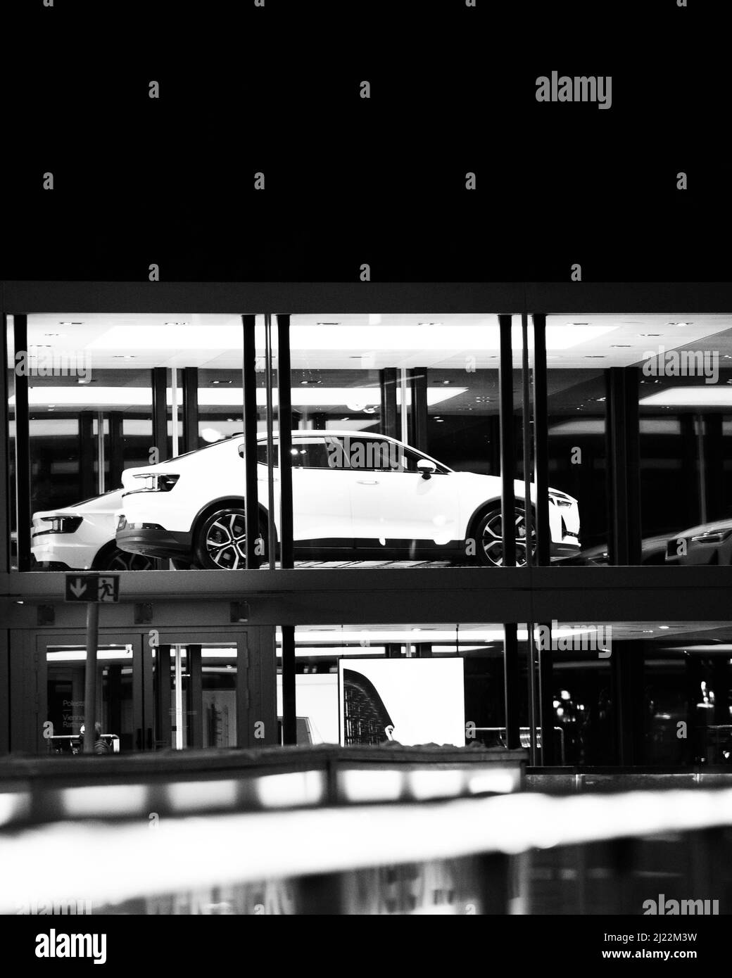 A vertical grayscale shot of a white car standing in front of the