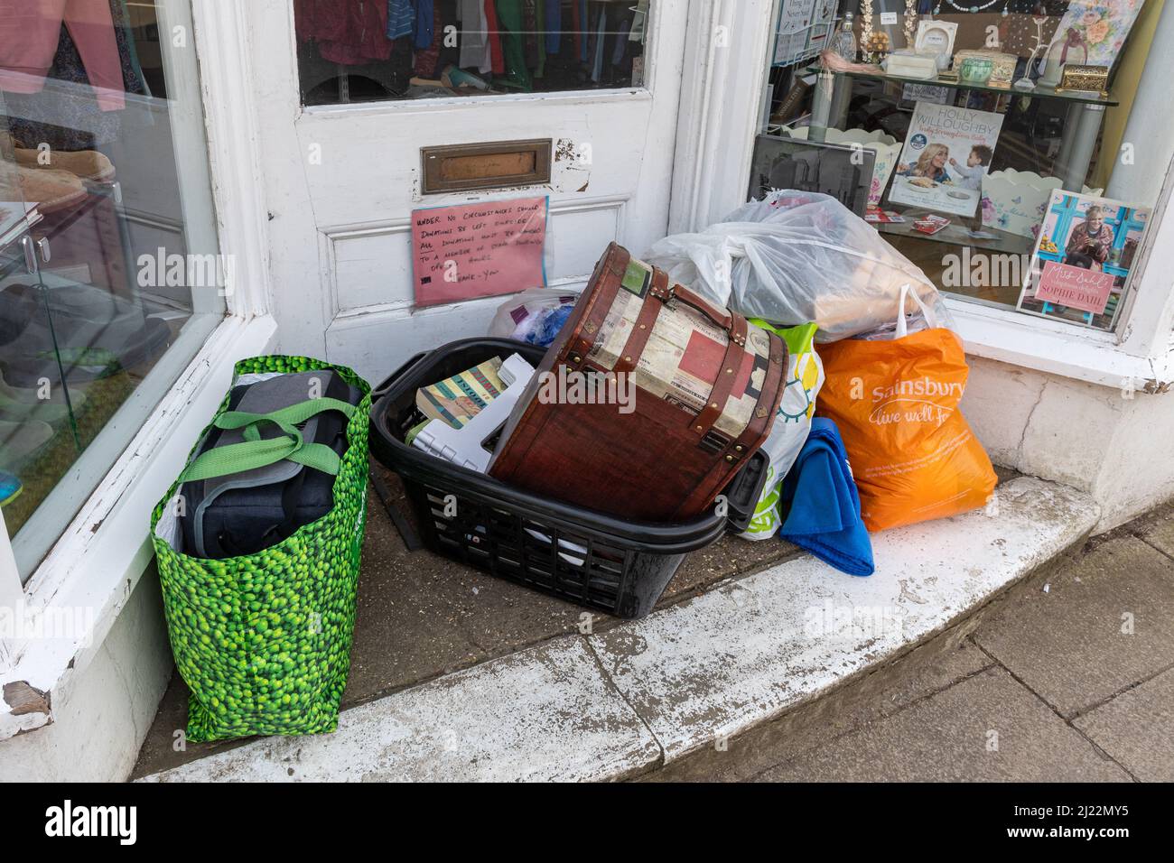Bags of donated second hand goods left in the entrance to a charity shop despite a notice asking people not to do this, UK Stock Photo