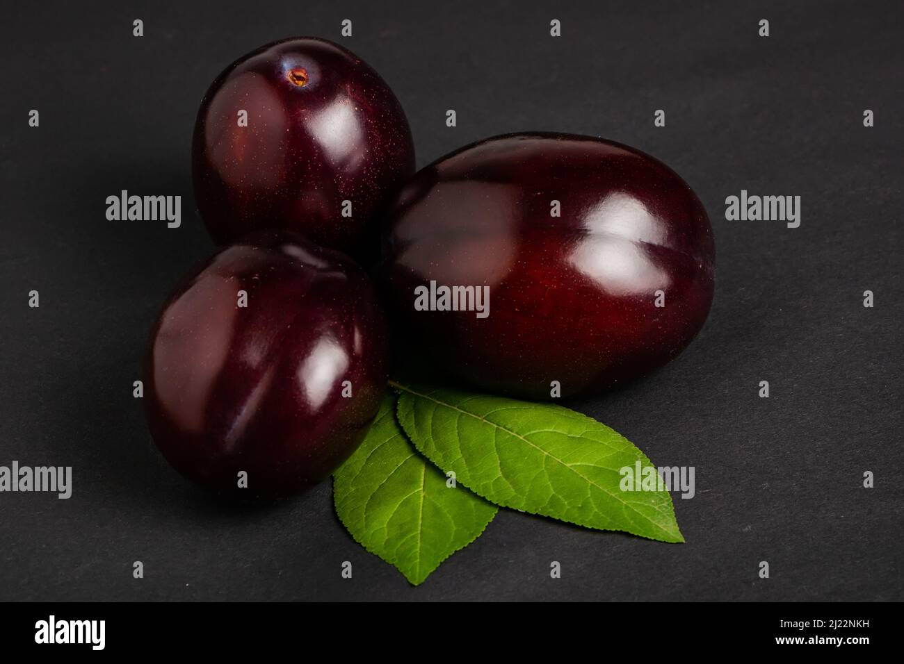 Plums with plum leaves on a dark background Stock Photo