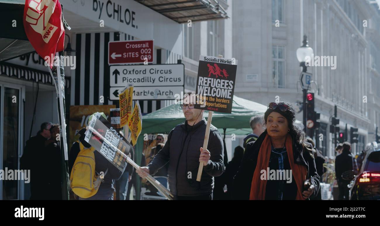 London, UK - 03 19 2022:  A man protester at Portland Place holding a sign, Socialist Worker… Refugees Welcome…’, for the yearly ‘March Against Racism'. Stock Photo
