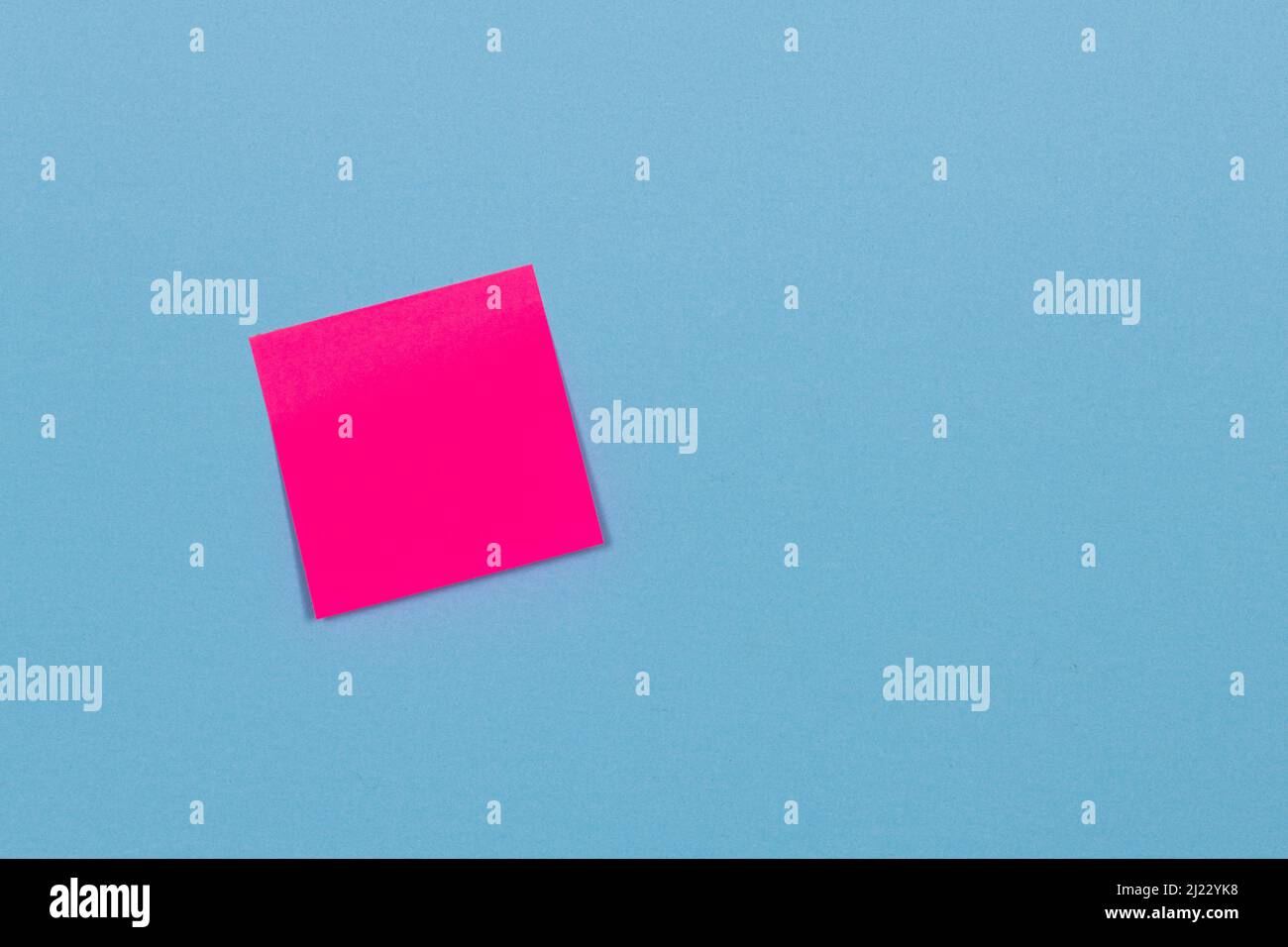 red adhesive paper note stuck to a blue background. Stock Photo
