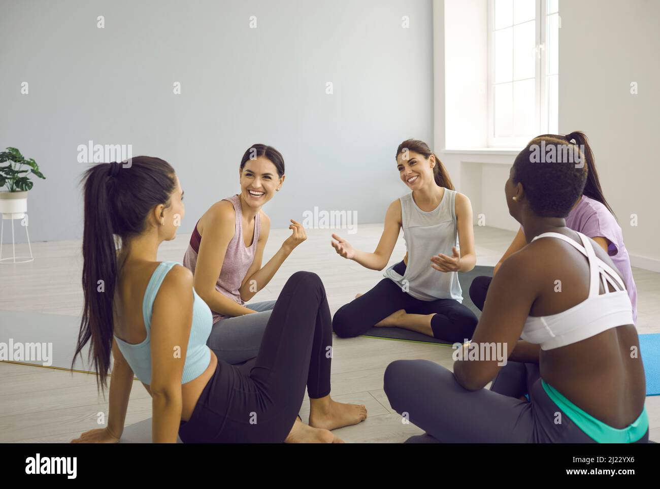 Women laughing together while sitting on yoga mats in a fitness