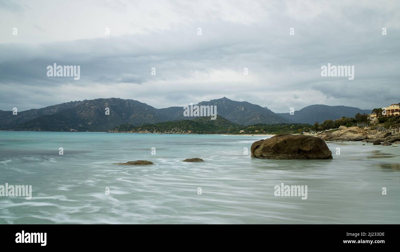 A cloudy spring day at Villasimius beach in Sardinia, Italy. The Mediterranean coastal view and sandy beach make for a serene nature scenery. Stock Photo