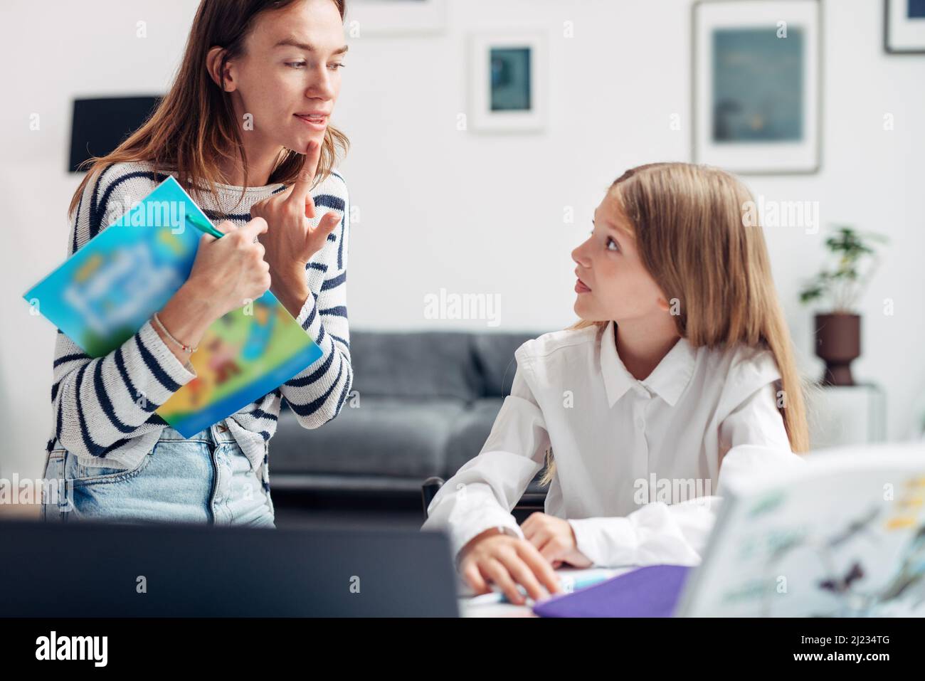 Woman teaches girl correct pronunciation of sounds or letters. Speech therapist or learning English. Stock Photo