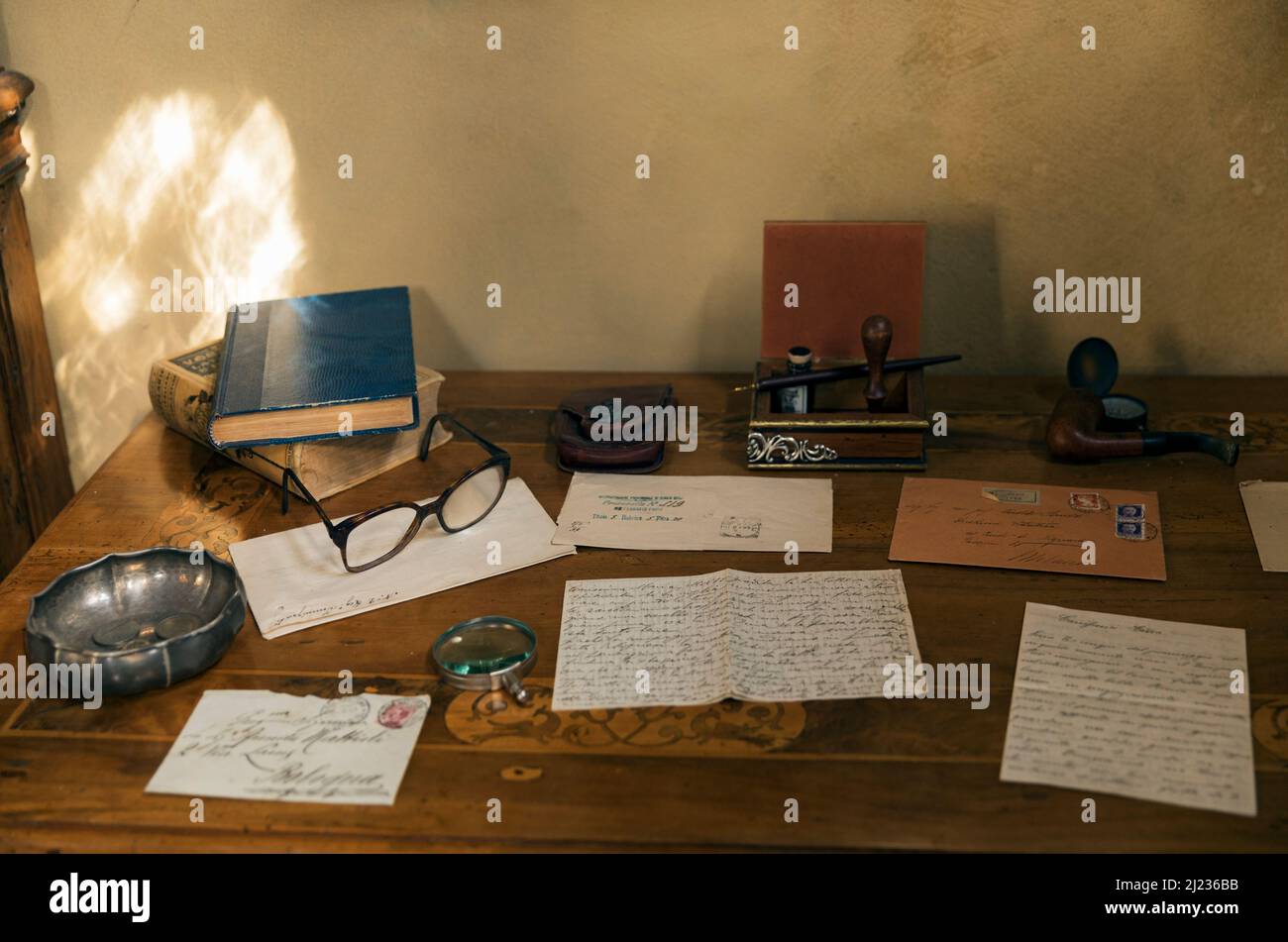 still life of a writing desk with books, letters, pen and ink eye glasses and a pipe Stock Photo