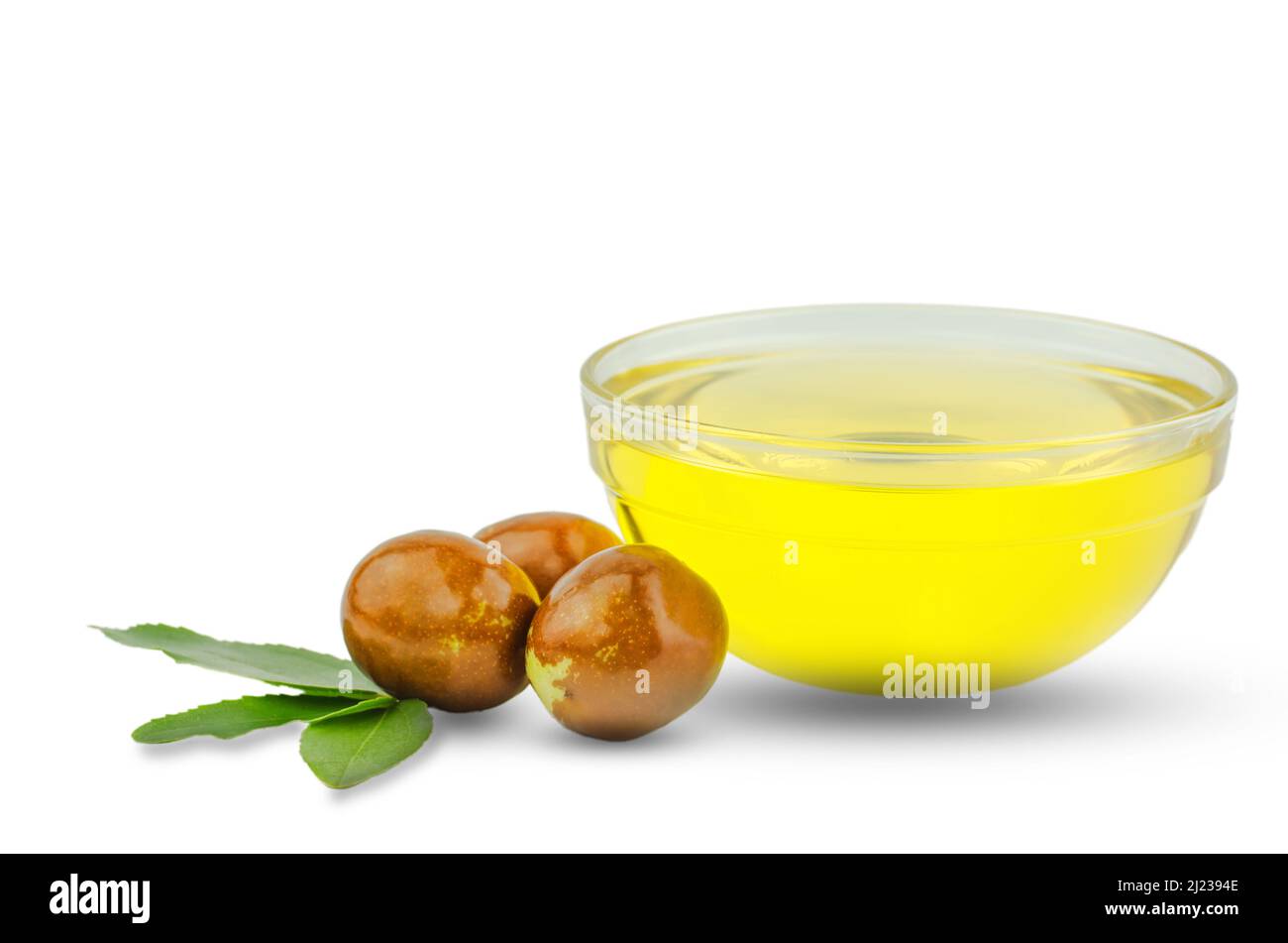 Bowl with jojoba oil and ripe fruits on white background Stock Photo