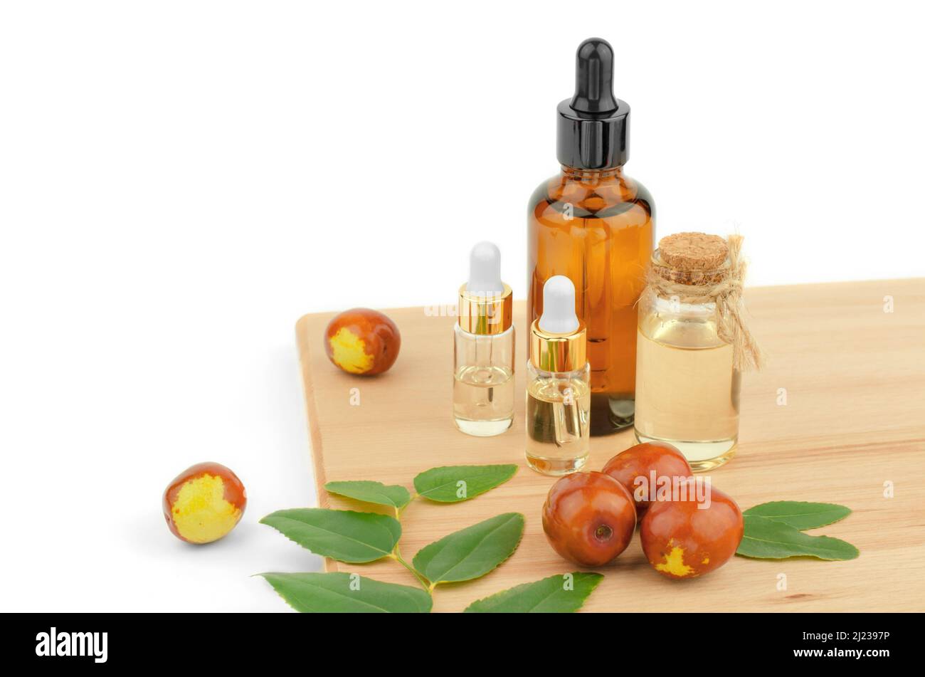 Jojoba oil bottles. Jojoba oil and fresh jojoba fruit on wooden table Stock Photo