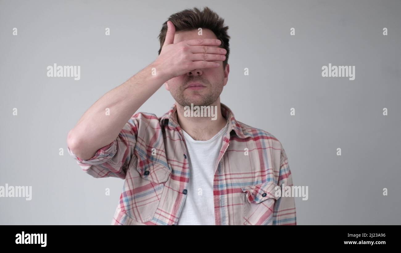 Young man covering his face by hand Studio shot Stock Photo - Alamy