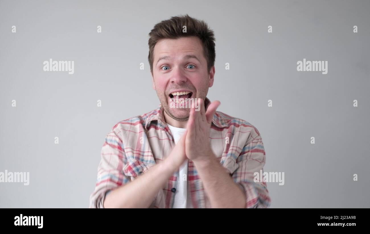 Young man smiling with glee as he rubs his hands together. Great news concept Stock Photo