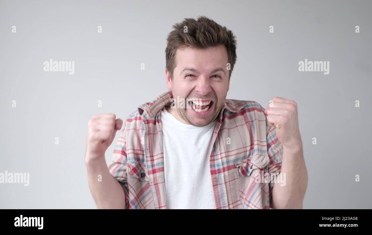 Successful emotional young caucasian man raising clenched fists in the ...
