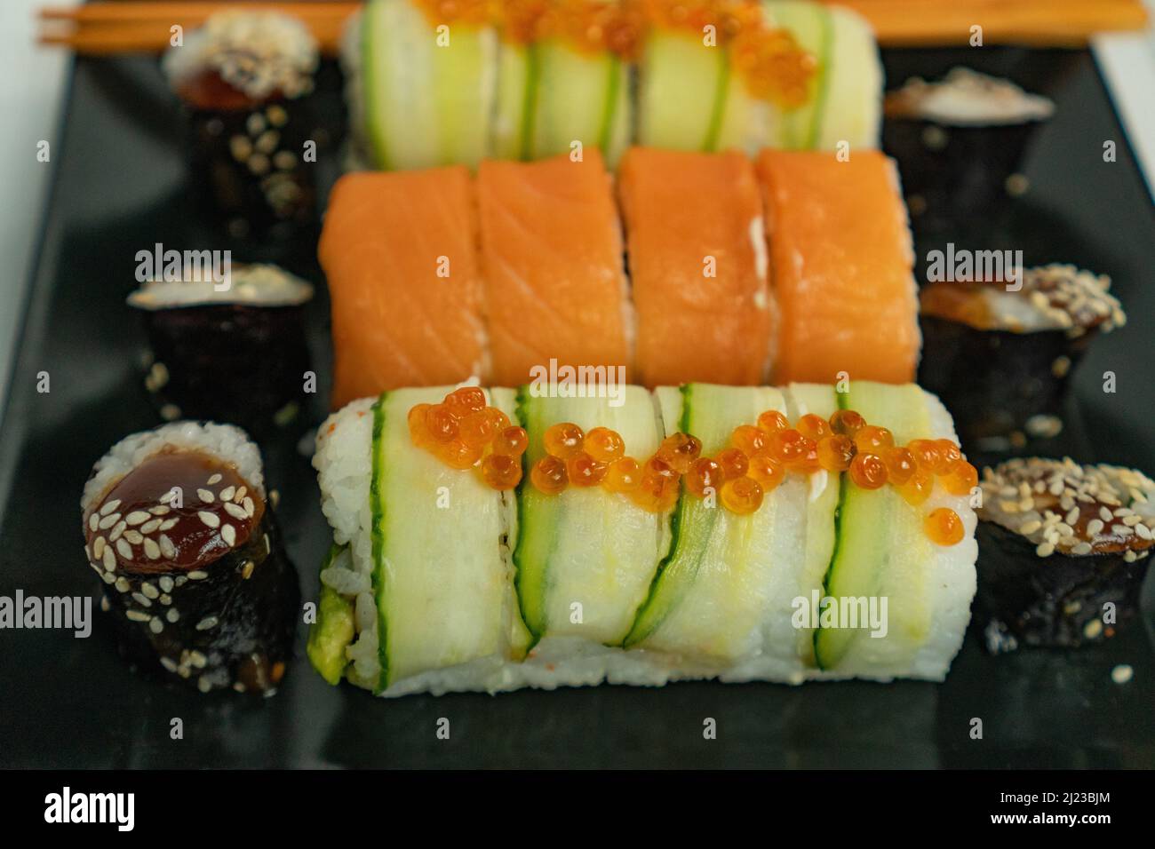 Sushi set with salmon, on a white wooden background in a black plate ...