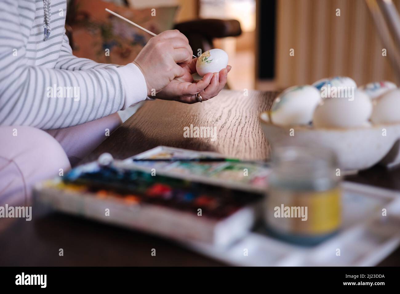 Process of woman paiting a water colors on fantasy chicken eggs. Female preparing for Easter egg festival Stock Photo