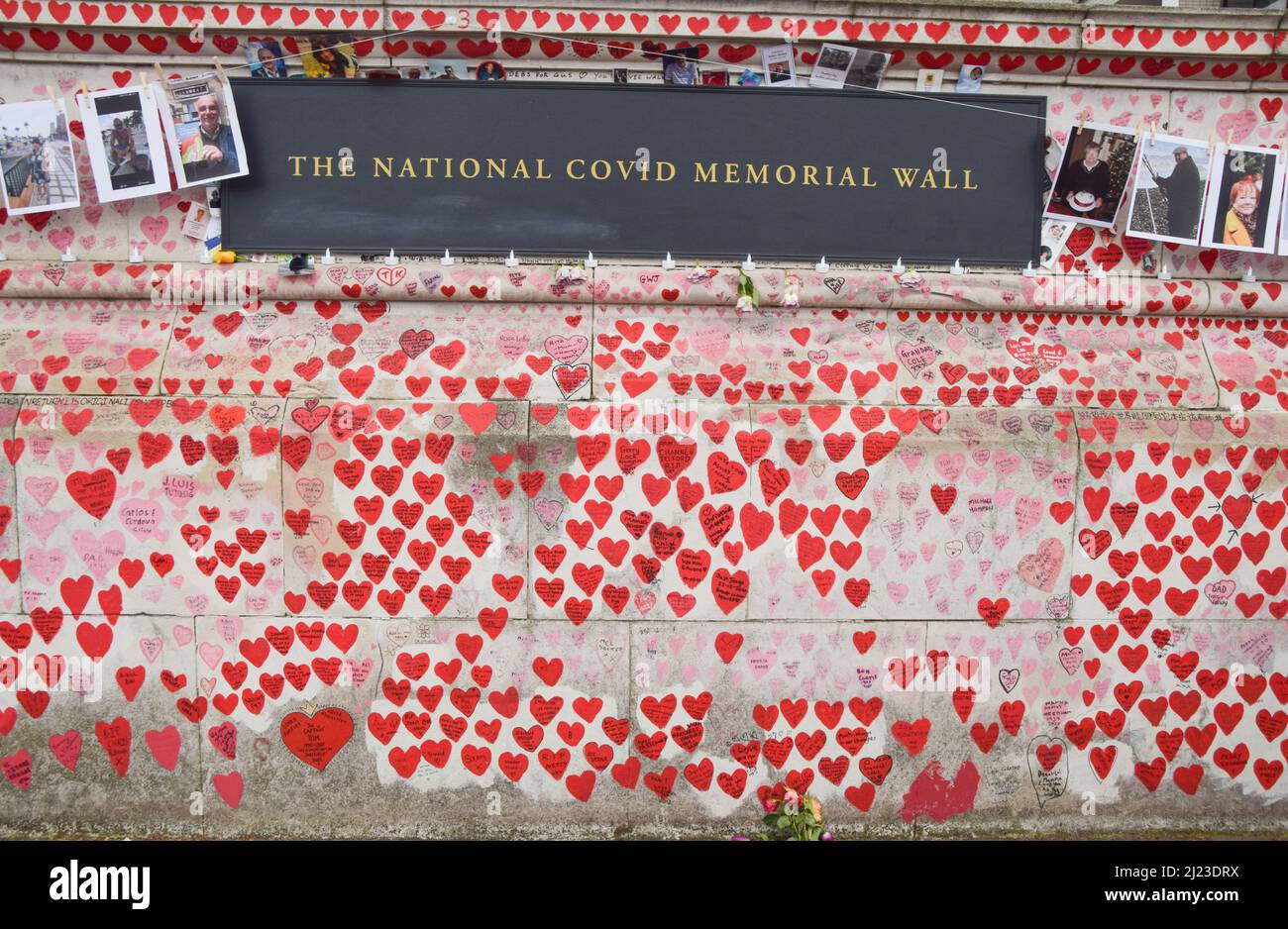 London, UK. 29th March 2022. Photos of people who lost their lives to coronavirus have been hung on the National Covid Memorial Wall to mark one year since the memorial was created. Over 150,000 red hearts have been painted on the wall to date, one for each life lost to Covid-19. Credit: Vuk Valcic/Alamy Live News Stock Photo