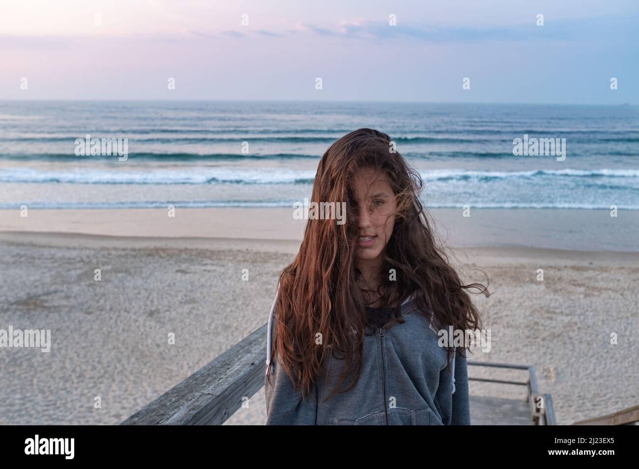 Young woman on the beach wind blows up her hair cover half face seascape Stock Photo