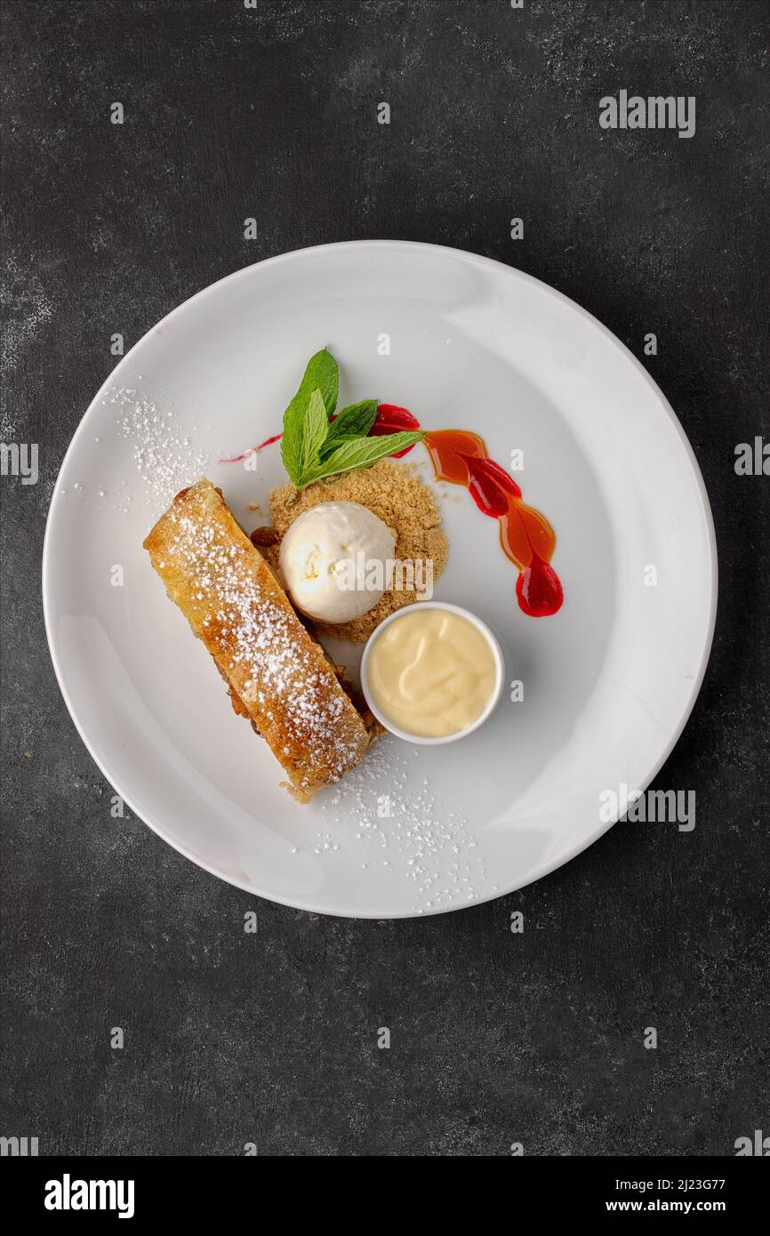 Dessert strudel with apples, ice cream, mint and condensed milk, on a