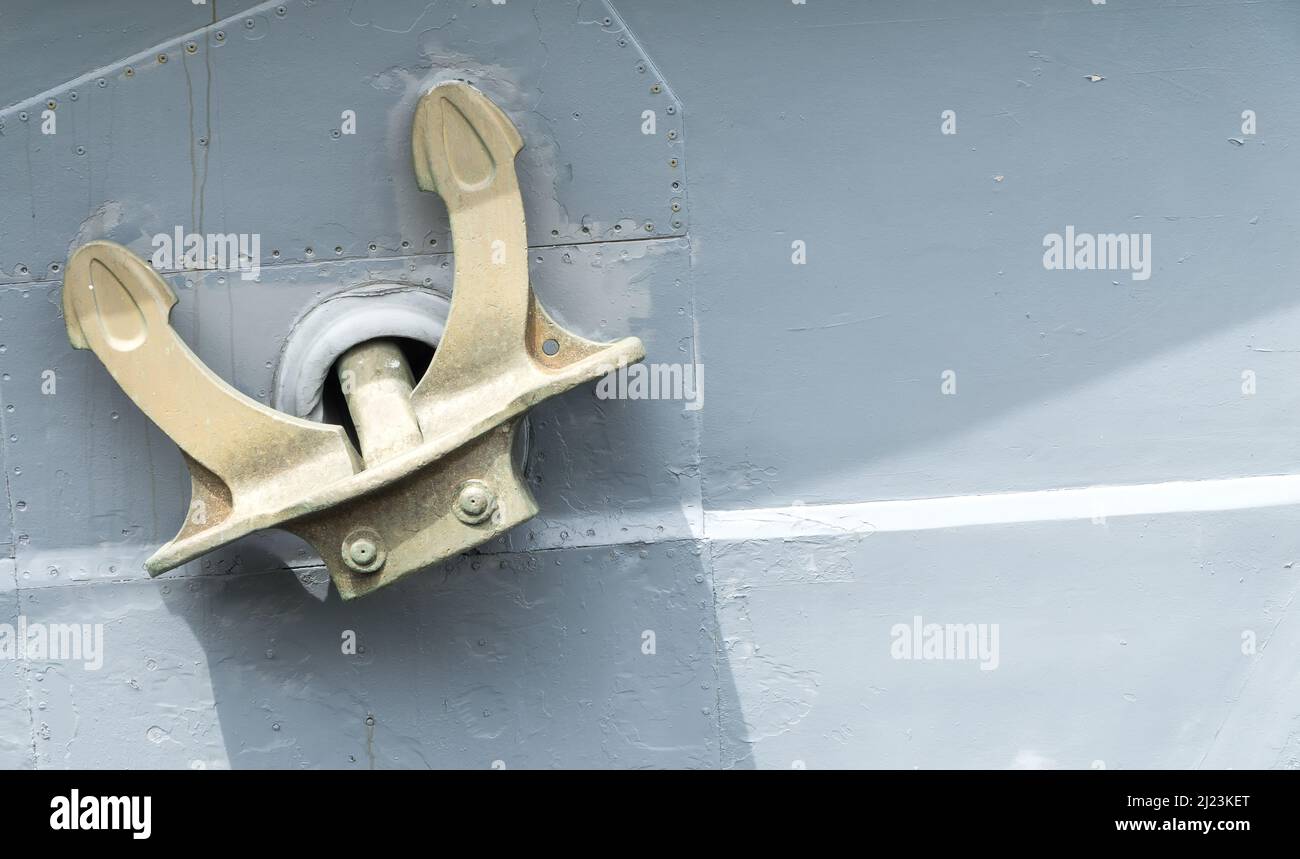 Close up of gold-painted mooring anchor on grey painted ship's side. Stock Photo