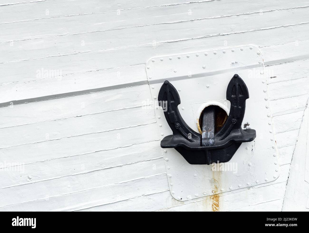 Close up of a black mooring anchor on white painted ship's side. Stock Photo