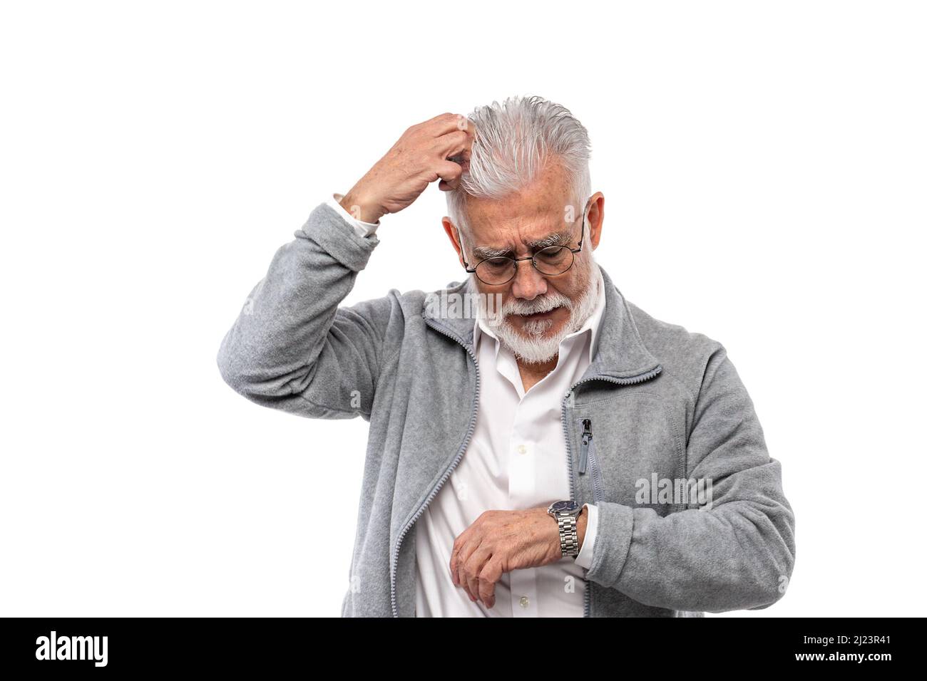 An elderly stylish man, gray-haired and with a beard, scratches his head and looks at his watch. The concept of punctuality and discipline. Stock Photo