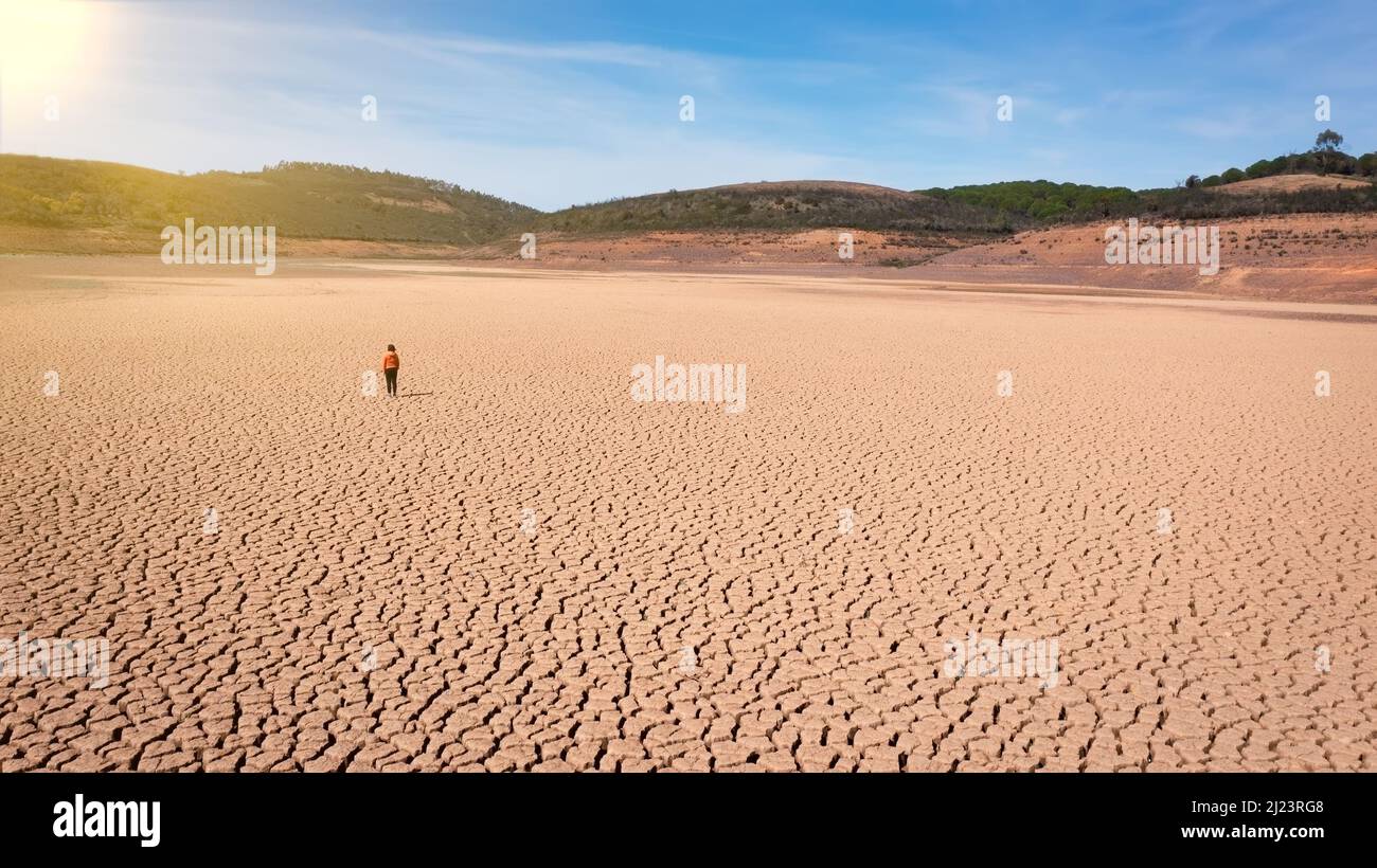 Silhouette of a man on a sandy cracked empty not fertile land during a drought. The concept of ecological catastrophe on the planet. Sunny day Stock Photo