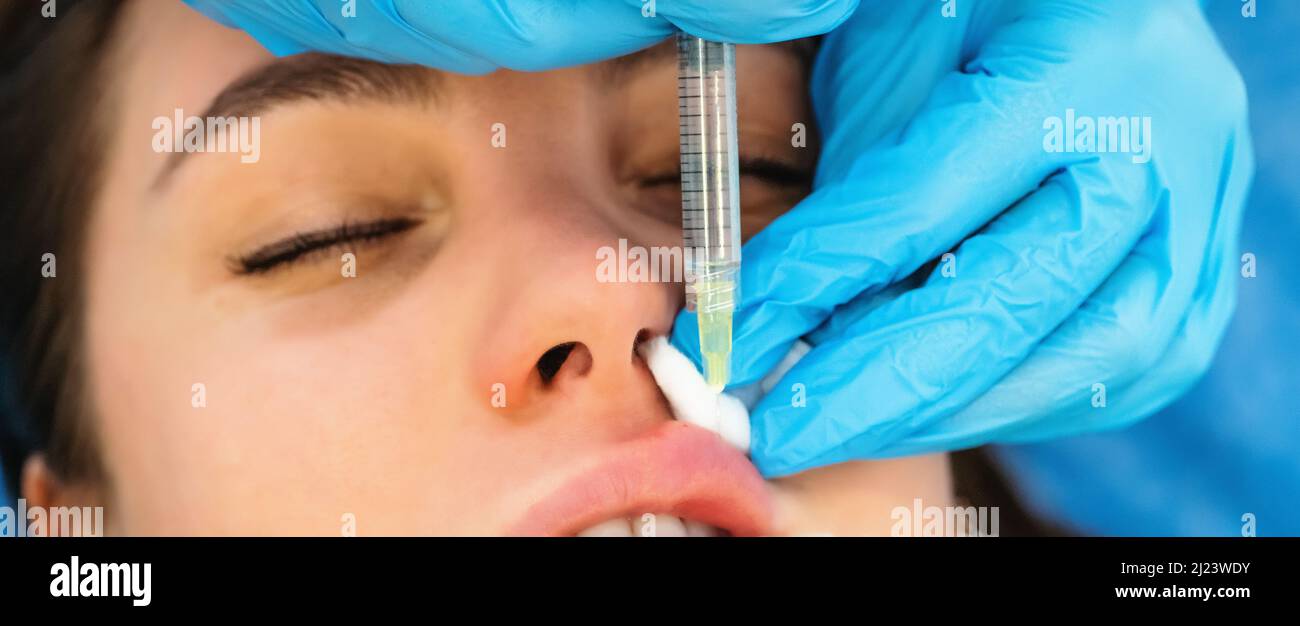 Young woman gets hyaluronic filler or botox cosmetic injection in lips, close up. Rejuvenating facial treatment. Stock Photo