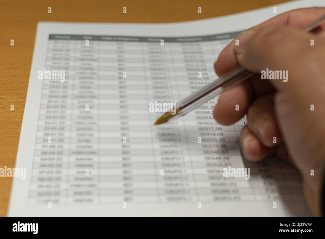 person reviewing an accounting sheet with number report on the office desk to see expenses and profits Stock Photo