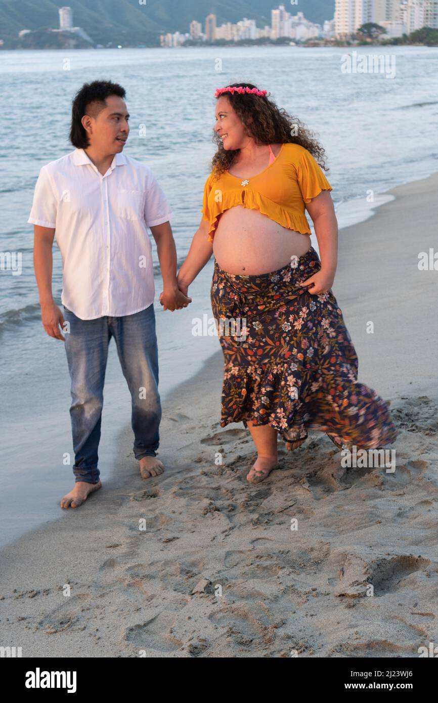 Pregnant couple walking on beach Stock Photo