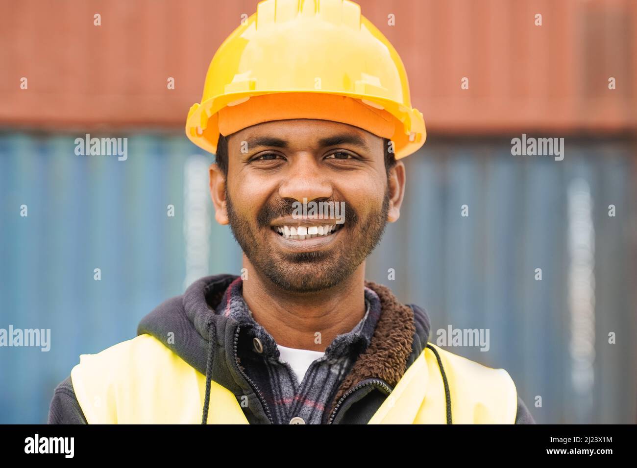 Happy Indian industrial worker man smiling at camera at shipping freight terminal port - Focus on face Stock Photo