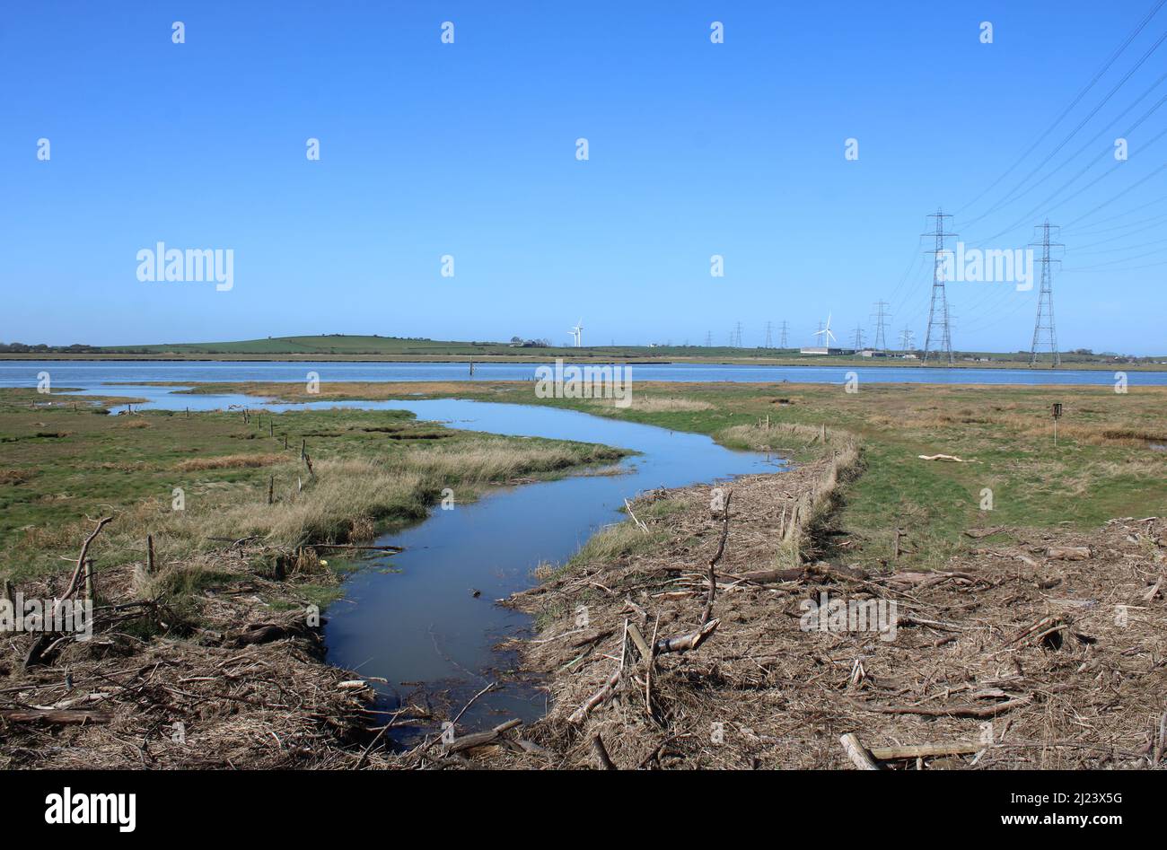 National grid electricity transmission power lines and pylons crossing the River Lune at Stodday near Lancaster with high tide in the river. Stock Photo