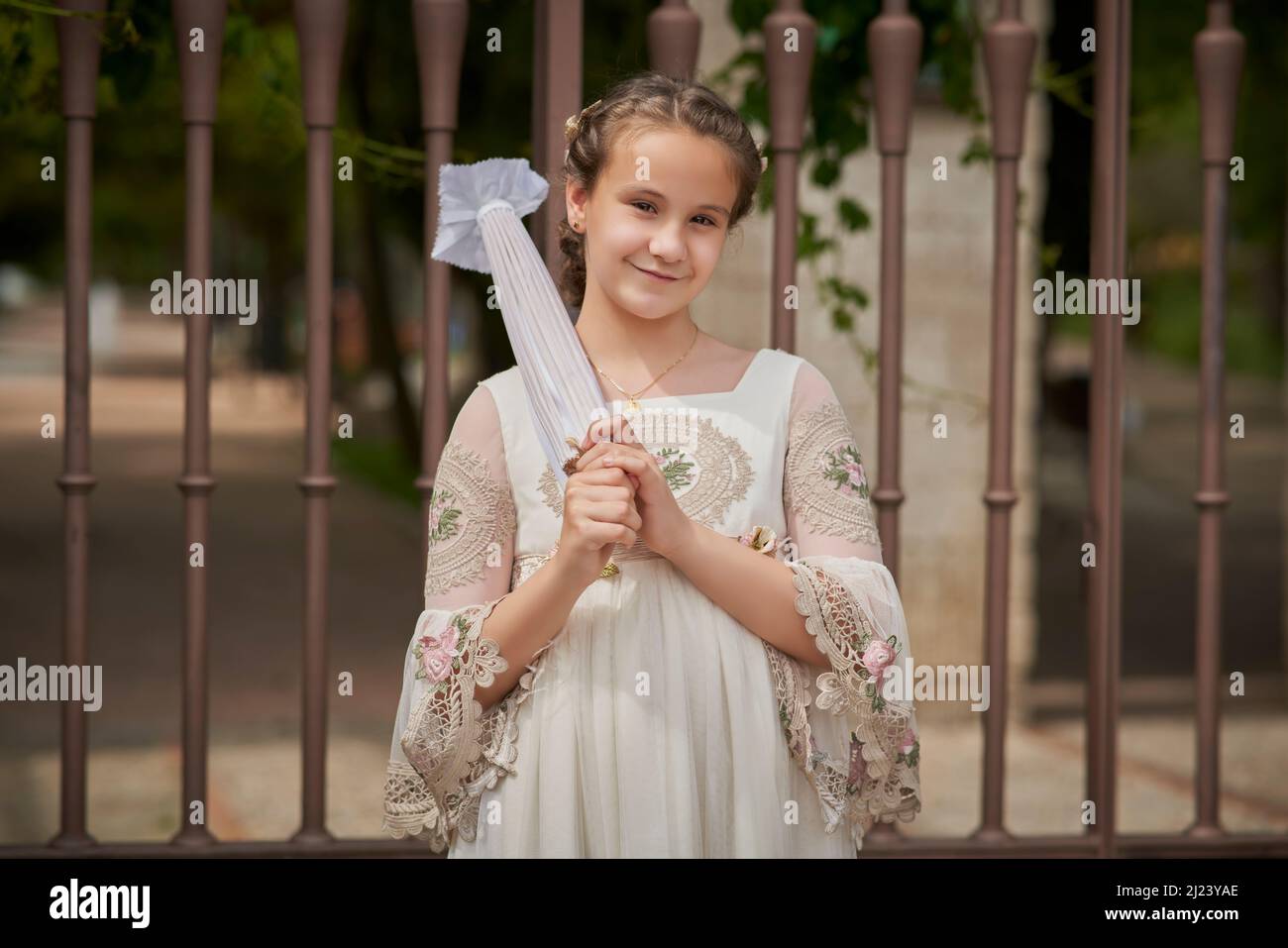 Communion girl posing with a white umbrella in a park Stock Photo